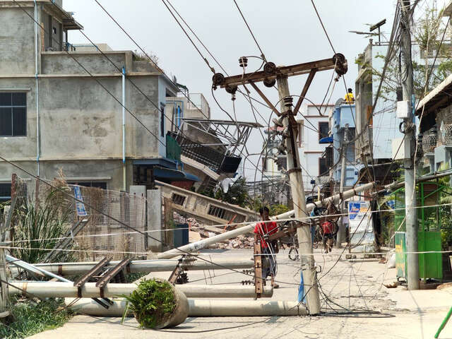 En man undersöker en nedfallen kraftledning som orsakats av jordbävningen i Myanmar.